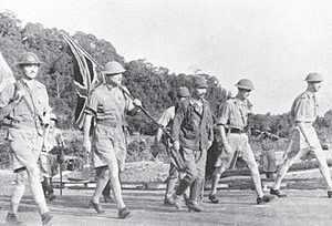 Archive photograph of officers marching under a flag, February 1942