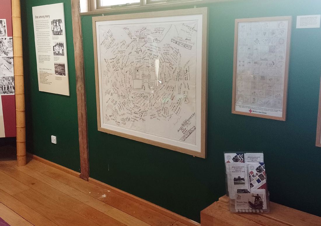 The framed embroidered tablecloth, covered in signatures, on display in the FEPOW Memorial Building